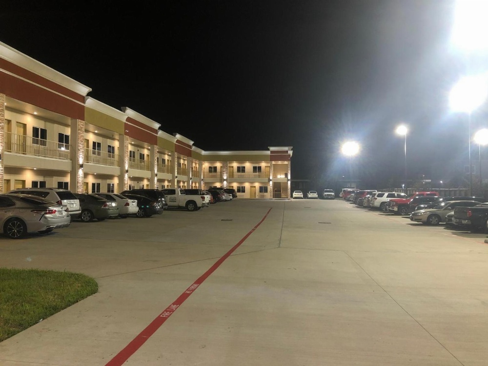 A two-story building with balconies and parking lot at night