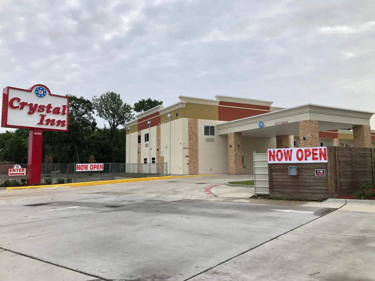 A photo of the exterior of a hotel with a sign and parking lot.